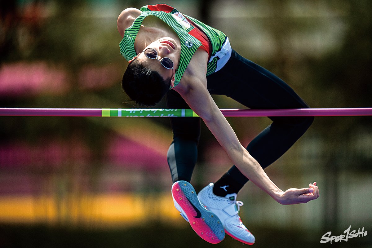 這位跳高選手，姿勢美妙， 再加一副黑超，更甚者，背景剛有一輛鮮艷顏色的雙層巴士經過，為一個全綠的背景，多加一點色彩，在運動攝影師的角度，絕對是可遇而不可求。